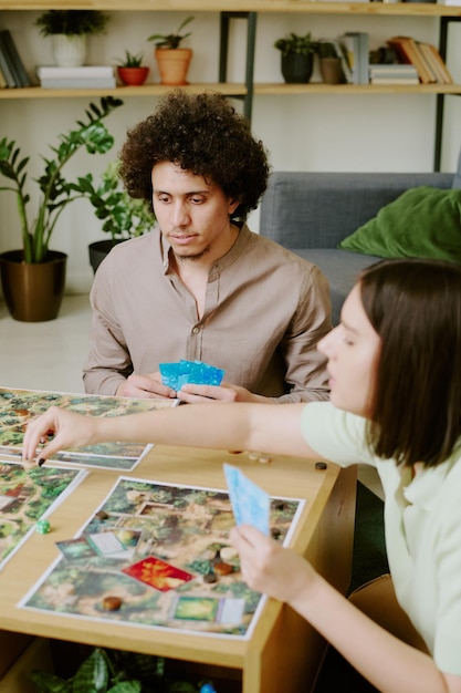 Detailed image showing a split-screen view of two players collaboratively solving a puzzle in a lush, green game environment. One player is controlling a character that is lifting a large stone, while the other character is navigating a pathway revealed by the lifted stone. The scene highlights the teamwork and problem-solving focus of modern co-op games.