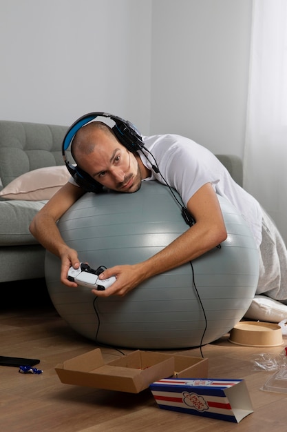 A person meditating in a room filled with gaming equipment, emphasizing the balance between mental wellness and gaming.