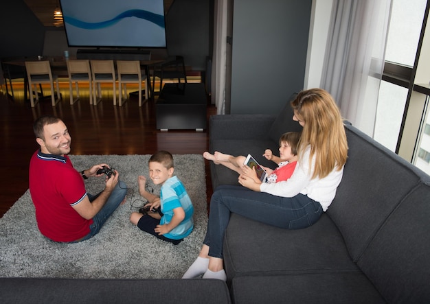A living room setup featuring an Xbox Series X connected to a 4K TV. A family is shown playing a game together, with two adults and two children holding controllers.