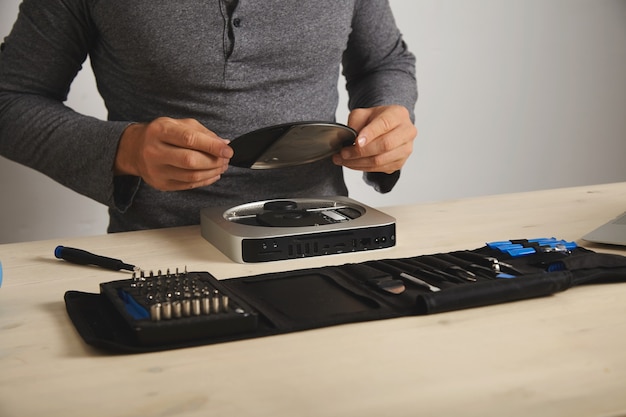 A person carefully disassembling a PlayStation 4 console on a desk, highlighting the internal components and tools used for the repair.