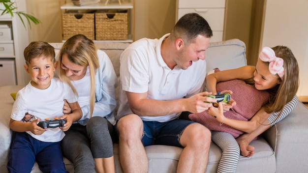 A family playing a Nintendo Switch game together, each holding a single Joy-Con. The focus is on their hands holding the controllers and their expressions of enjoyment.