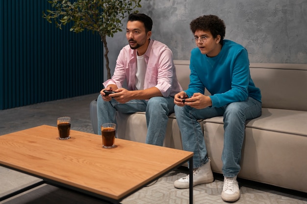 A close-up shot of two game controllers resting on a coffee table in front of a television during a splitscreen gaming session. The controllers are modern and ergonomic, with visible wear and tear, indicating frequent use. The television screen displays a racing game in splitscreen mode, with two distinct perspectives clearly visible. The overall image captures the sense of competition and camaraderie associated with local multiplayer gaming.