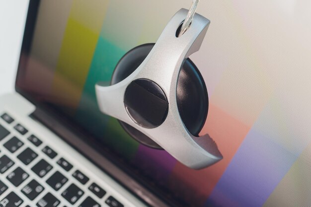 A photo of a colorimeter device attached to a gaming monitor screen during the calibration process. The device is positioned in the center of the screen, measuring the color output and providing feedback to the calibration software.