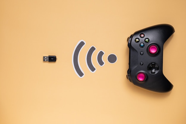A close-up shot of an Xbox Wireless Controller connected to a gaming PC via USB. The controller is in focus, highlighting its buttons, analog sticks, and overall ergonomic design. The background shows a blurred image of the gaming PC setup with RGB lighting.
